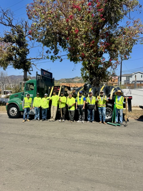 Cleanup volunteers gathered beside a Builders FirstSource truck